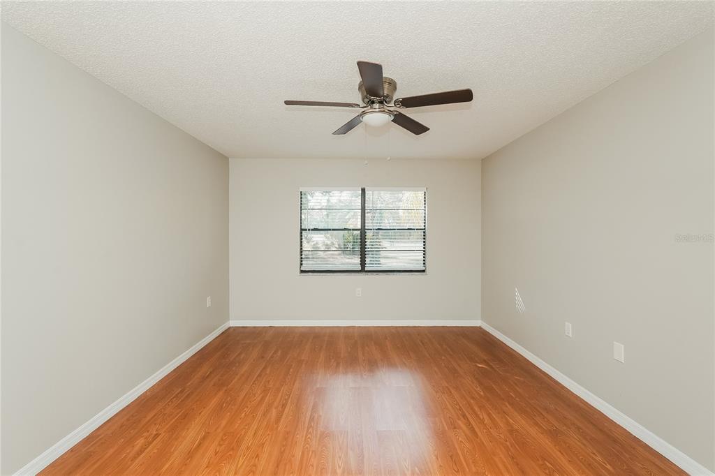 12165 Rockford Street Spring Hill, FL 34608 - Photo 10 of 16 an empty room with wooden floor ceiling fan and windows
