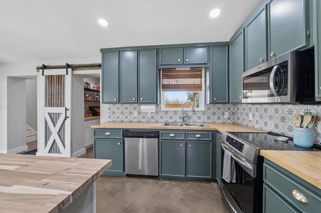286 Benevolence Way China Spring, TX 76633 - Photo 8 of 37 Modern kitchen featuring teal cabinetry, wood-finish countertops, stainless steel appliances, and a patterned tile backsplash
