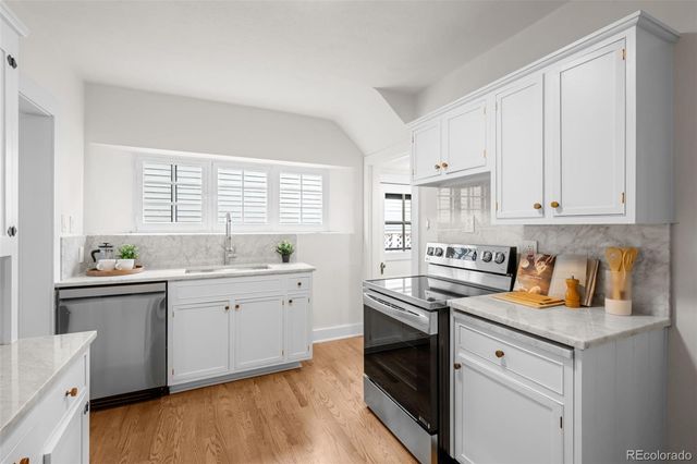 a kitchen with granite countertop white cabinets and white appliances