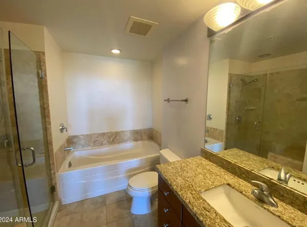 a bathroom with a granite countertop bathtub sink vanity mirror and toilet