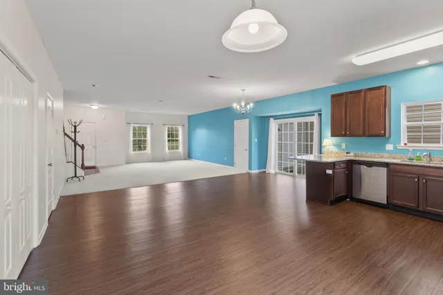 a kitchen with stainless steel appliances granite countertop wooden cabinets a sink dishwasher a stove and a refrigerator with wooden floor