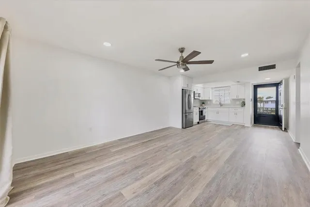 a view of empty room with wooden floor and ceiling fan