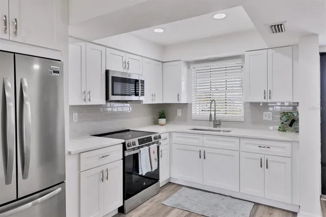 a kitchen with white cabinets stainless steel appliances and a window