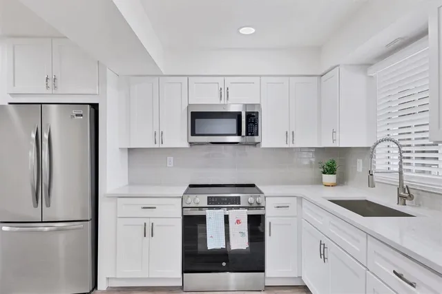 a kitchen with white cabinets and stainless steel appliances