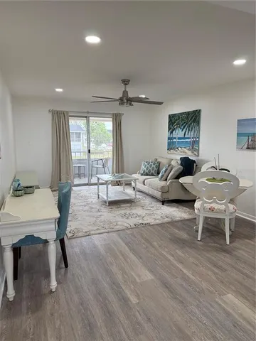 a living room with furniture a large window and wooden floor