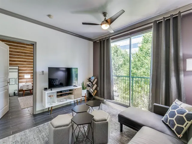 a living room with furniture a flat screen tv and a large window