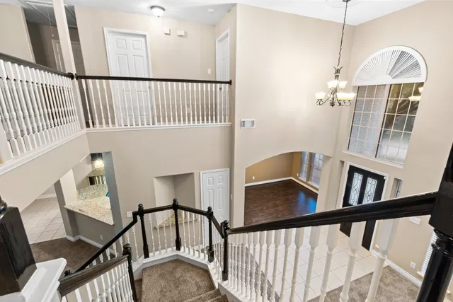 a view of a white house with a small yard and large trees