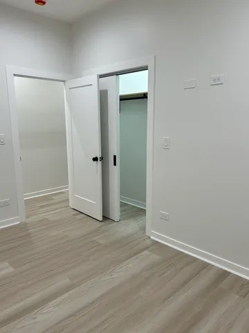 a view of an empty room with wooden floor and closet area