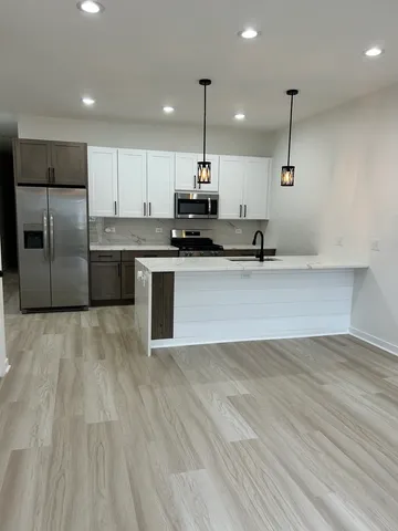 a kitchen with kitchen island a sink and a stove top oven with wooden floor