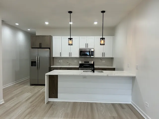 a view of kitchen with stainless steel appliances granite countertop a sink a stove and a refrigerator