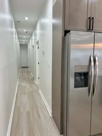 a view of hallway with stainless steel appliances wooden floor