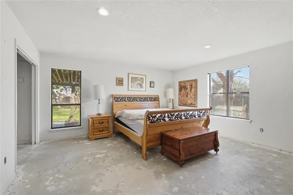 a bed sitting in a spacious bedroom next to a window