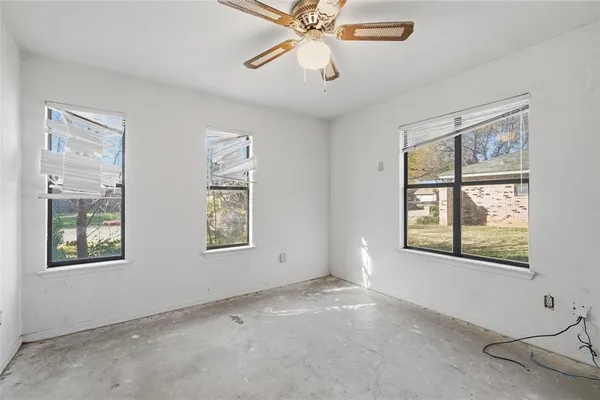 a view of an empty room with a window and a ceiling fan