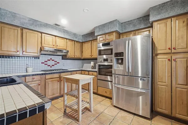 a kitchen with stainless steel appliances granite countertop a refrigerator sink and cabinets