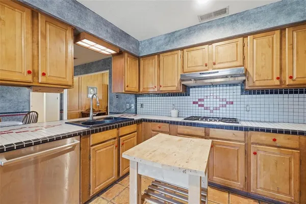 a kitchen with granite countertop a sink stainless steel appliances and cabinets