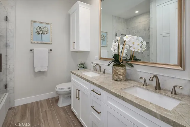 a bathroom with a double vanity sink a toilet and a shower
