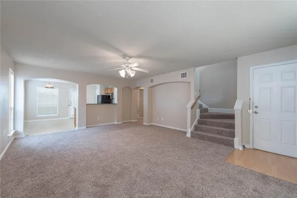 an empty room with staircase and ceiling fan