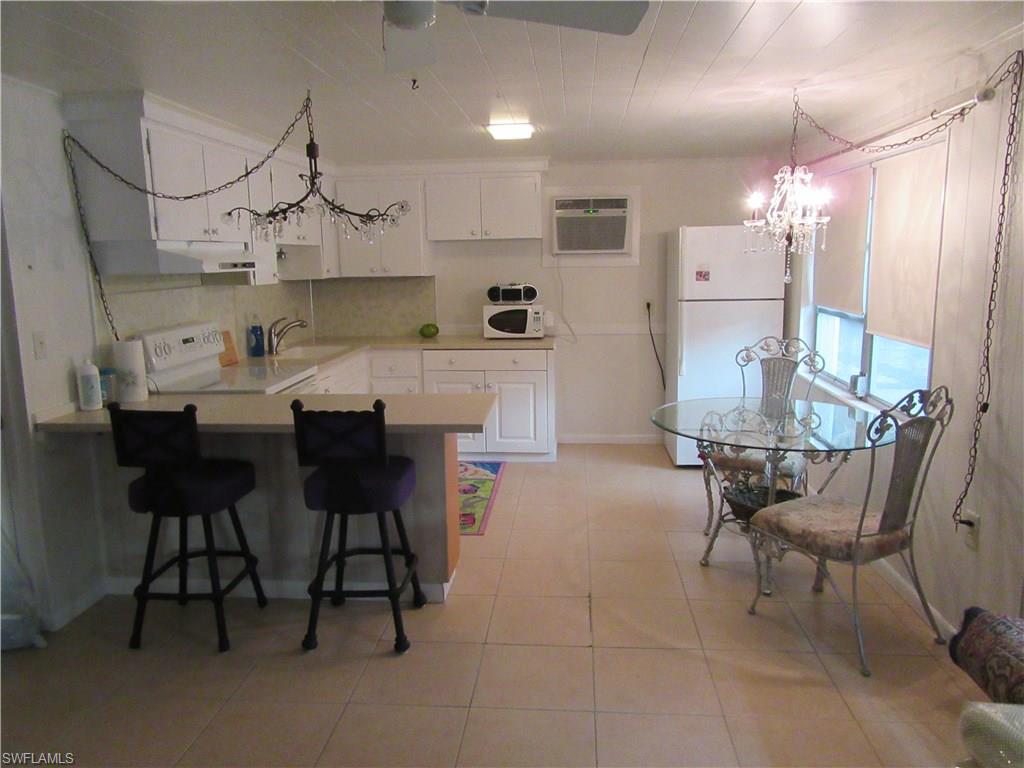 1009 Ridge Street Naples, FL 34103 - Photo 4 of 10 a kitchen with kitchen island a dining table chairs cabinets and stainless steel appliances
