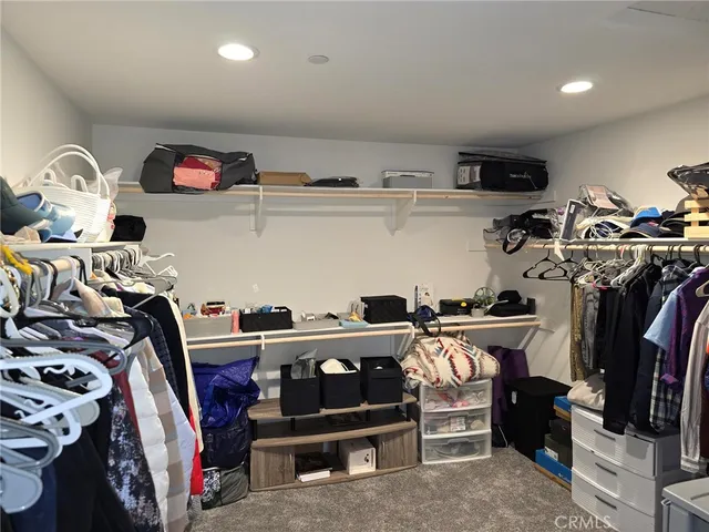 a view of walk in closet with clothes and shoes