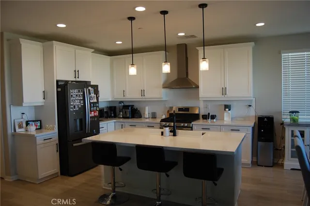 a kitchen with a refrigerator a sink a stove and chairs