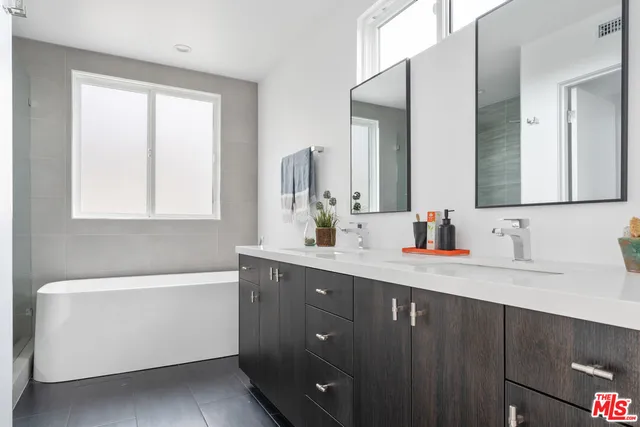 a bathroom with a double vanity sink a mirror and a bathtub