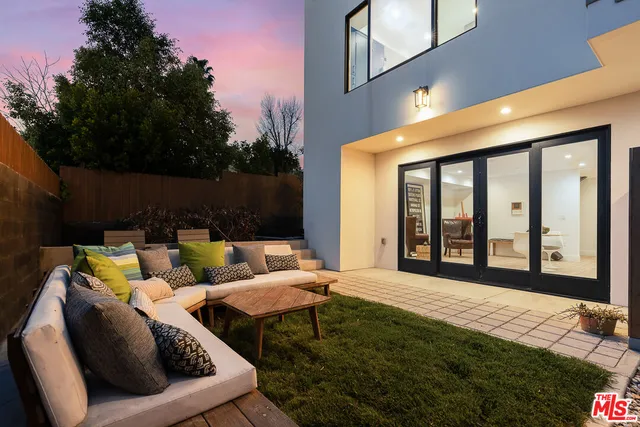 a view of a patio with couches chairs and floor to ceiling window and potted plants