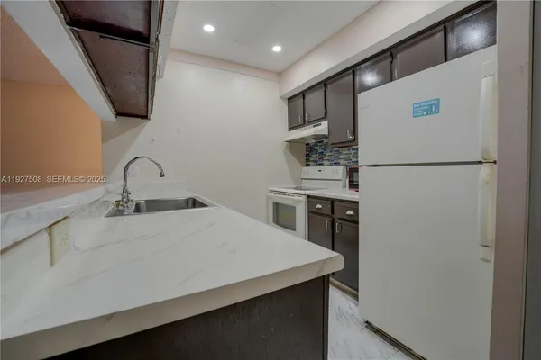 a kitchen with a sink a refrigerator and cabinets