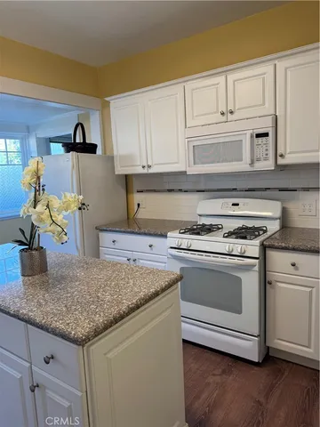a large kitchen with stainless steel appliances kitchen island a large counter top and a wooden floors