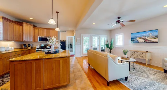 a living room with stainless steel appliances furniture a rug and a kitchen view