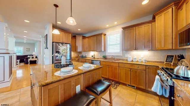 a kitchen with stainless steel appliances granite countertop a sink a stove and chairs