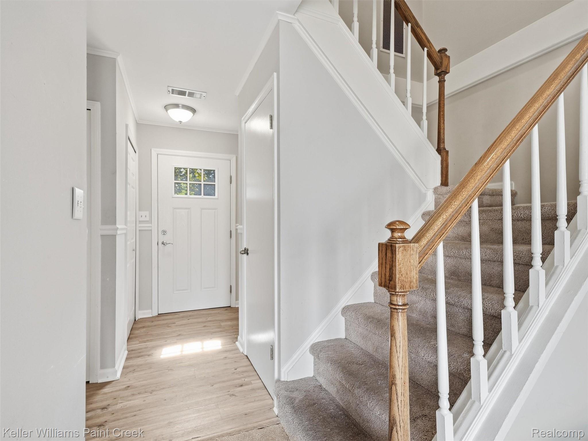 1208 Lear Court Rochester, MI 48307 - Photo 5 of 28 Entryway featuring wood-finish flooring, a paneled door with glass inserts, and a staircase with wood newel posts and handrails