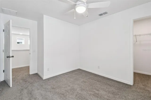 an empty room with closet and a chandelier fan