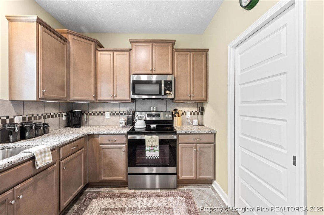5512 Tolarsville Road St. Pauls, NC 28384 - Photo 12 of 30 a kitchen with stainless steel appliances granite countertop a stove a sink and a microwave