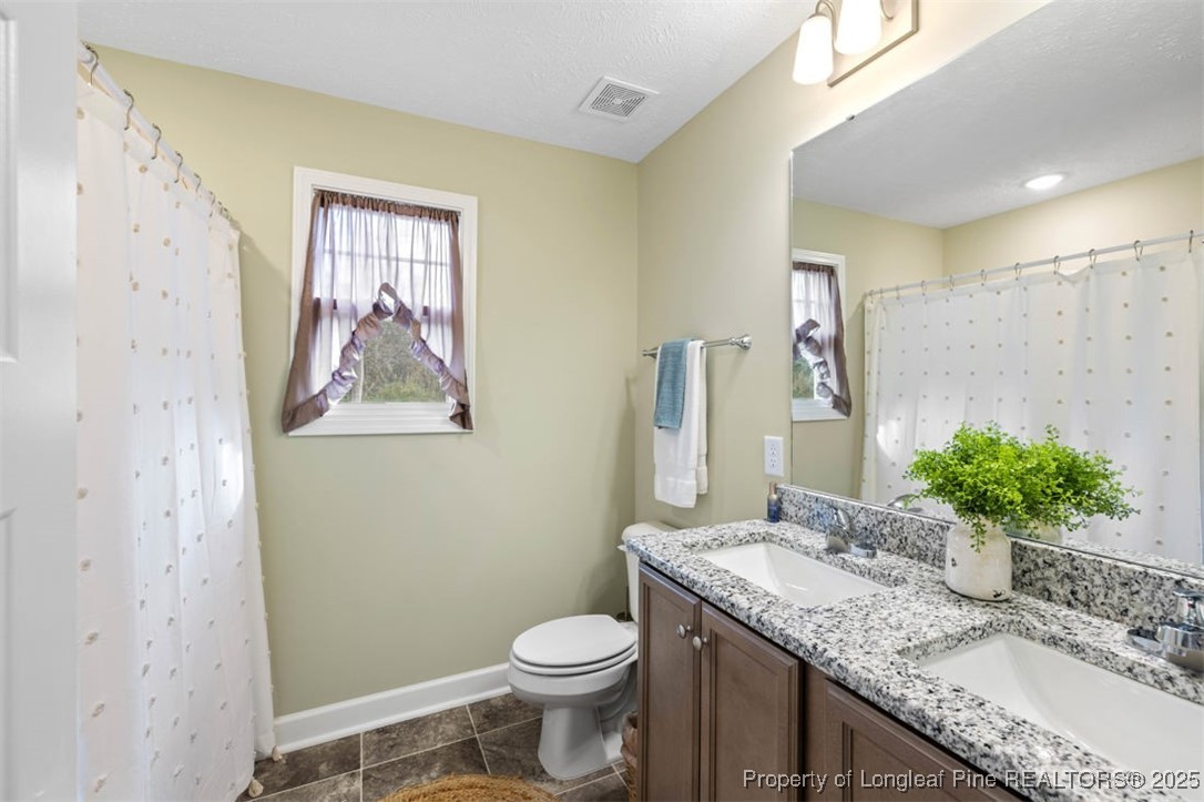 5512 Tolarsville Road St. Pauls, NC 28384 - Photo 17 of 30 a bathroom with a granite countertop sink toilet and a mirror