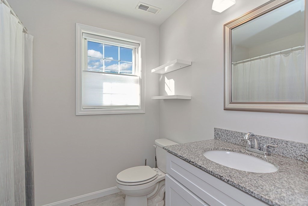 38 Riley Road, Unit 38 Tyngsboro, MA 01879 - Photo 8 of 25 a bathroom with a granite countertop toilet a sink and mirror