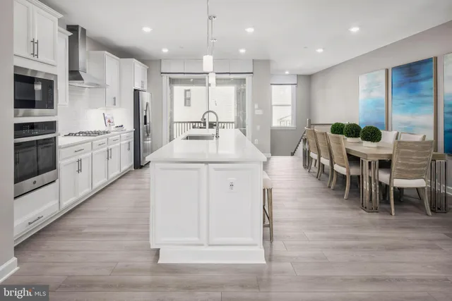 a large white kitchen with lots of counter space wooden floor and appliances