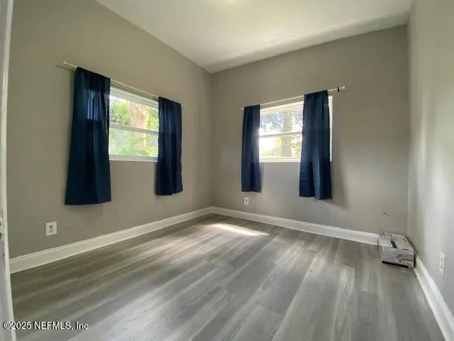 a view of an empty room with wooden floor and a window
