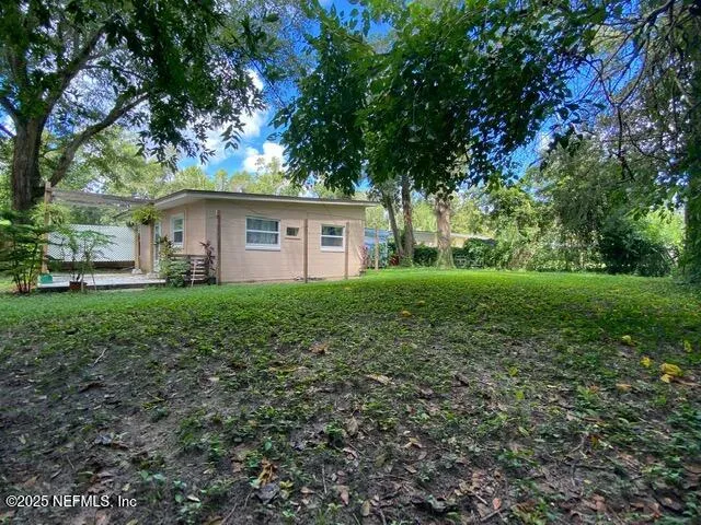 a backyard of a house with plants and large tree