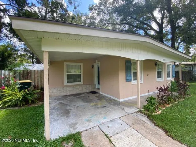 a view of a house with a yard plants and large tree