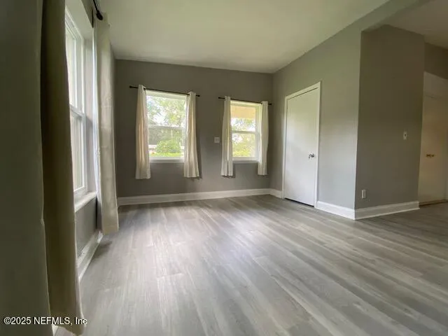 an empty room with wooden floor and windows