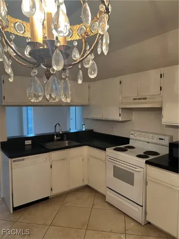 a kitchen with granite countertop a sink a stove and cabinets