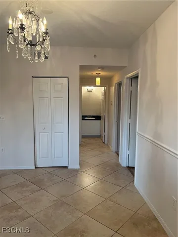a view of a hallway with wooden floor and chandelier