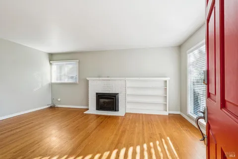 an empty room with windows and fireplace