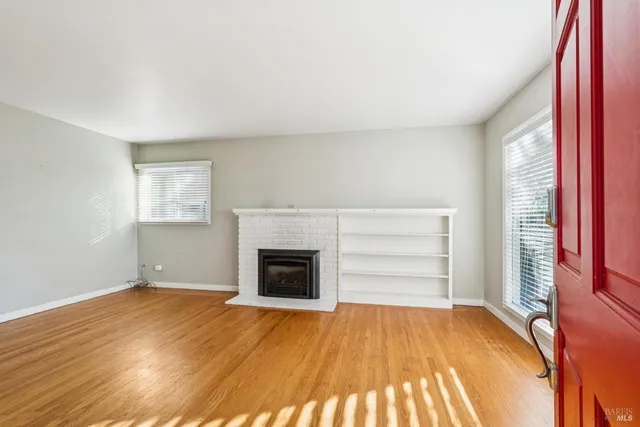 an empty room with windows and fireplace