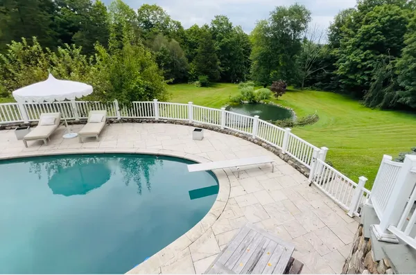a view of a swimming pool with a table and chairs under an umbrella