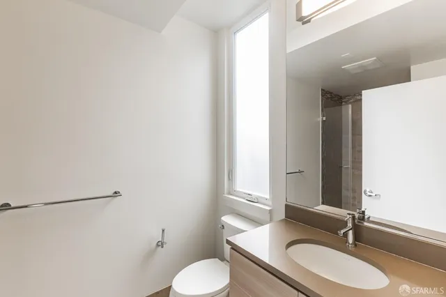 a bathroom with a granite countertop sink toilet and a mirror