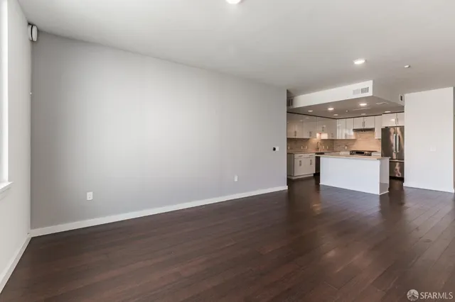 a view of a kitchen with a fridge and wooden floor