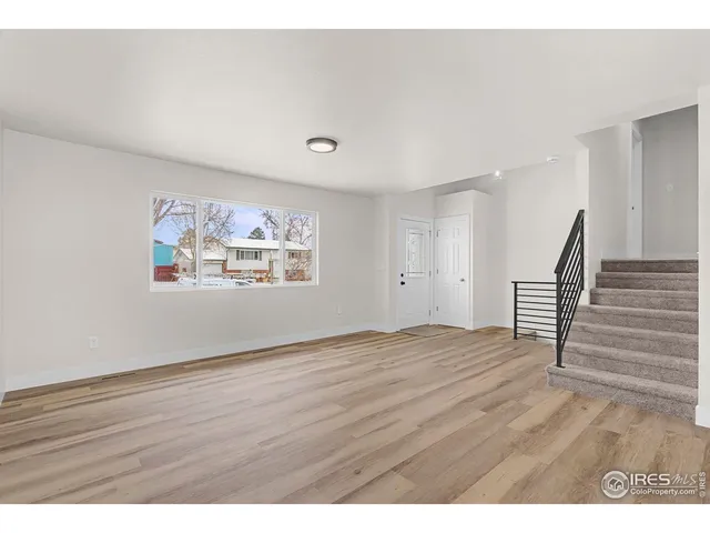 a view of an empty room with wooden floor and stairs