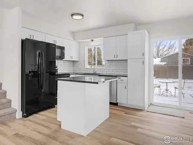 a kitchen with granite countertop a refrigerator stove and sink