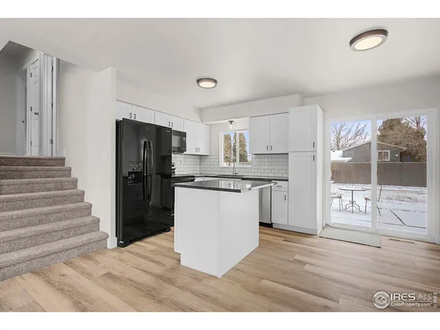 a kitchen with refrigerator and wooden floor